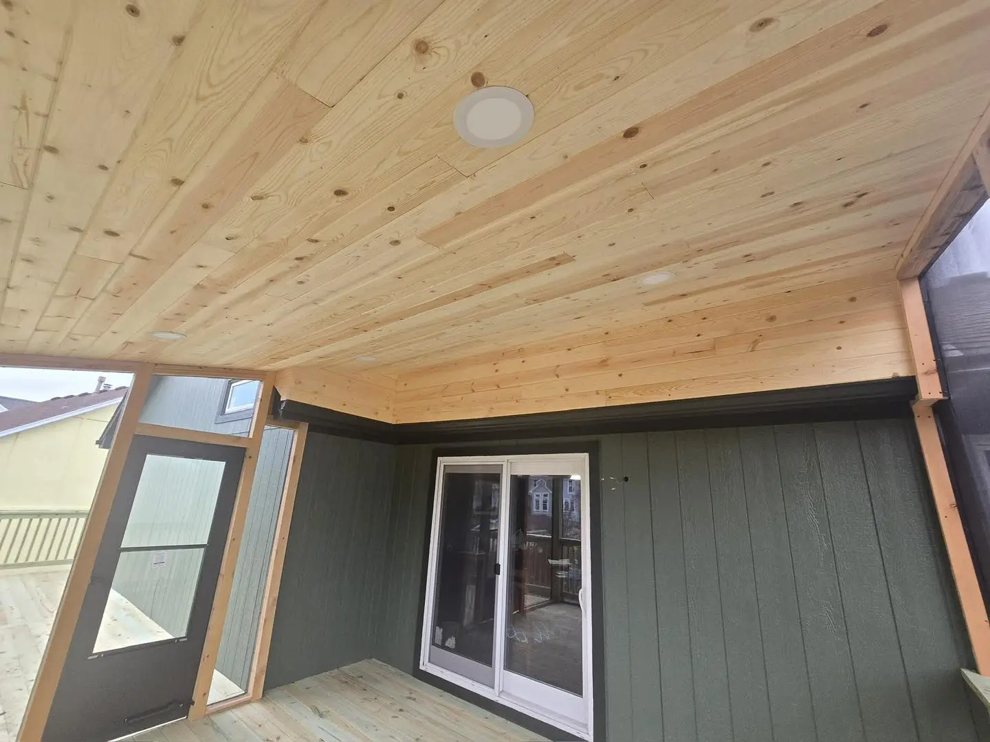 covered outdoor deck with natural wood ceiling and sliding glass door showing cedar wood grain detail in Kansas City home