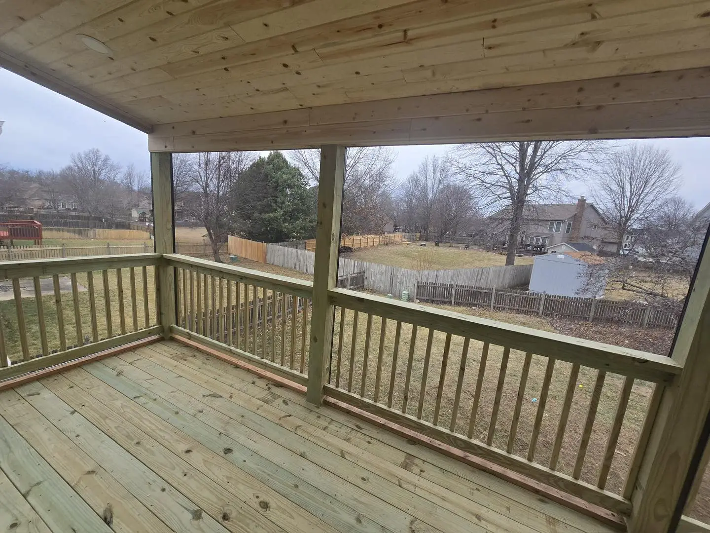 covered elevated wood deck overlooking fenced backyard demonstrating popular deck design ideas in Kansas City