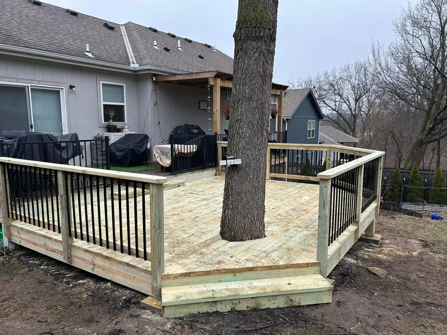 elevated wood deck with black railings built around a tree showing a well-maintained Kansas City deck