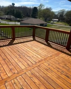 freshly stained elevated wood deck with black metal railings overlooking a suburban backyard area