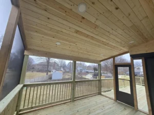screened deck with wood plank ceiling and railing overlooking residential backyard area